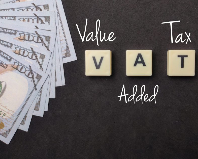 Banknotes and toys word with text VAT value added tax on black background.